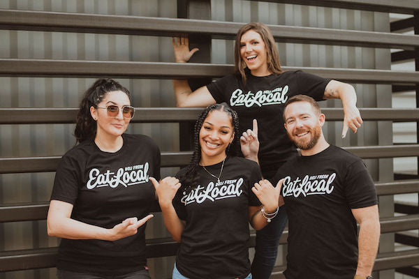 Group of people smiling wearing Black Eat Local T-shirts